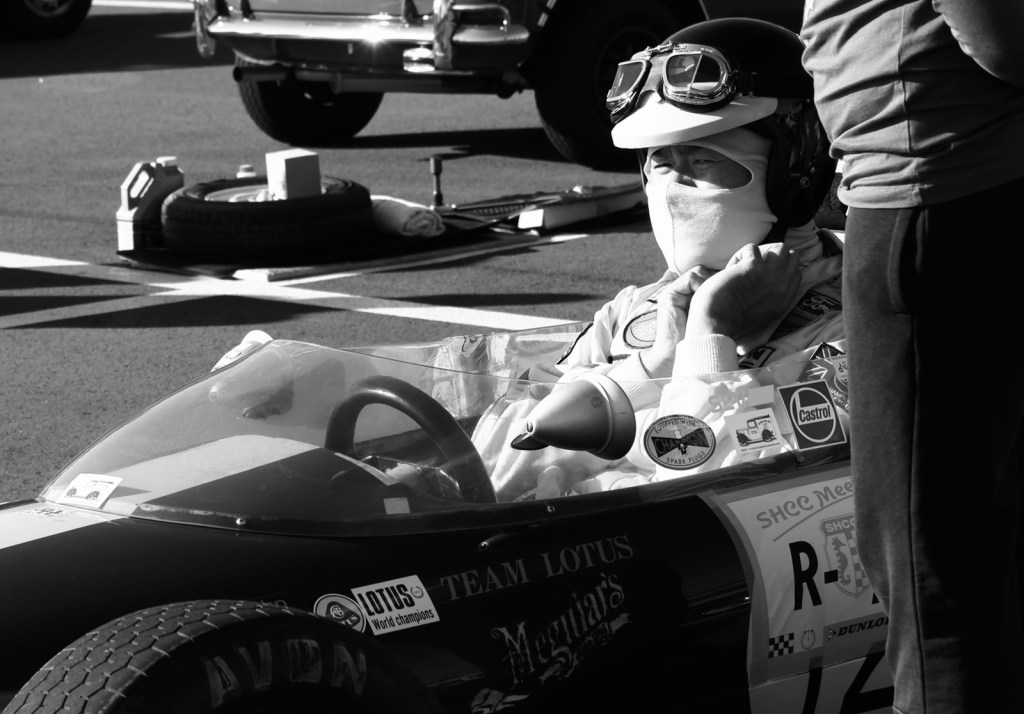 A driver sitting in a Lotus 51, securing his helmet.
