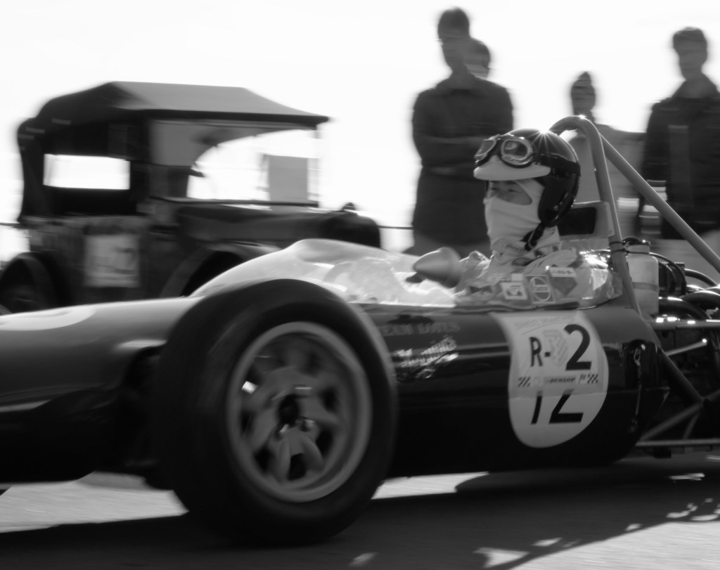 A Lotus 51 in motion in front of an Austin 7 Chummy.