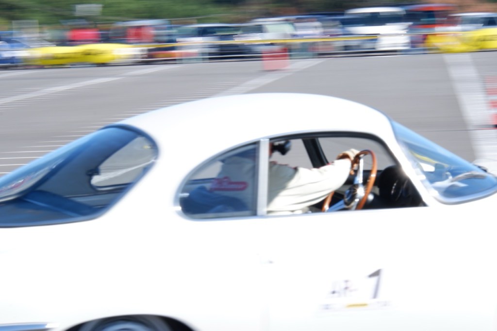 An elegant white 1960s Alfa Romeo Giulietta Sprint Speciale being driven at a classic car race event.
