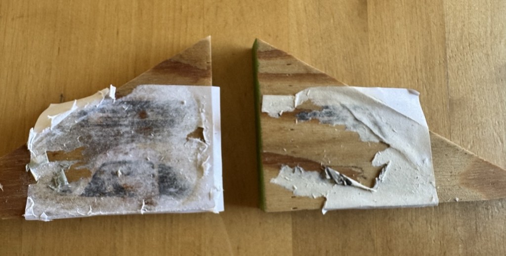 Two pieces of wood with paper glued on, looking messy.